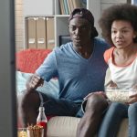 Young couple watching TV love videoblocks-teenage-african-couple-watching-live-sports-game-on-tv-at-home-and-getting-disappointed-about-their-team-losing_be9qemen9g_thumbnail-full01_Fotor