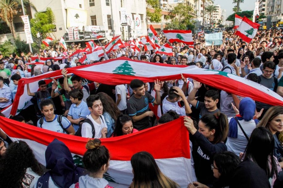 Lebanese students wave national flags as they gather in an a