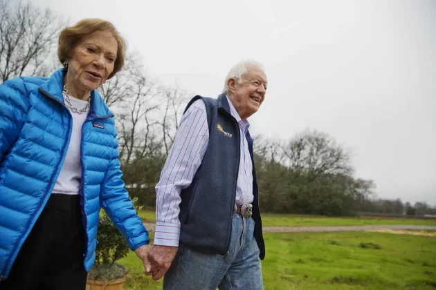 Former President Jimmy Carter, right, and his wife, Rosalynn, walk on