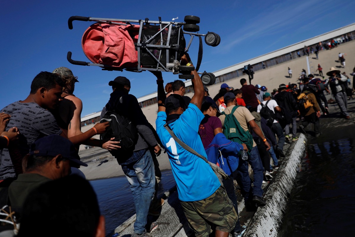 File IOM Migrants, part of a caravan of thousands traveling from Central America en route to the United States, make their way across Tijuana river near the border wall between the U.S. and Mexico in Tijuana, Mexico November 25, 2018. REUTERS/Edgard Garrido