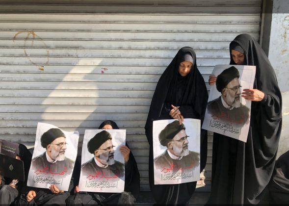 People hold portraits of Raisi as they mourn during the funeral procession. [Abedin taherkenareh/EPA]