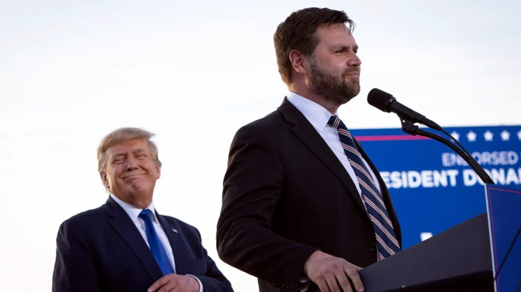 Ohio Senator JD Vance speaks to an audience with former President Donald Trump in the background.