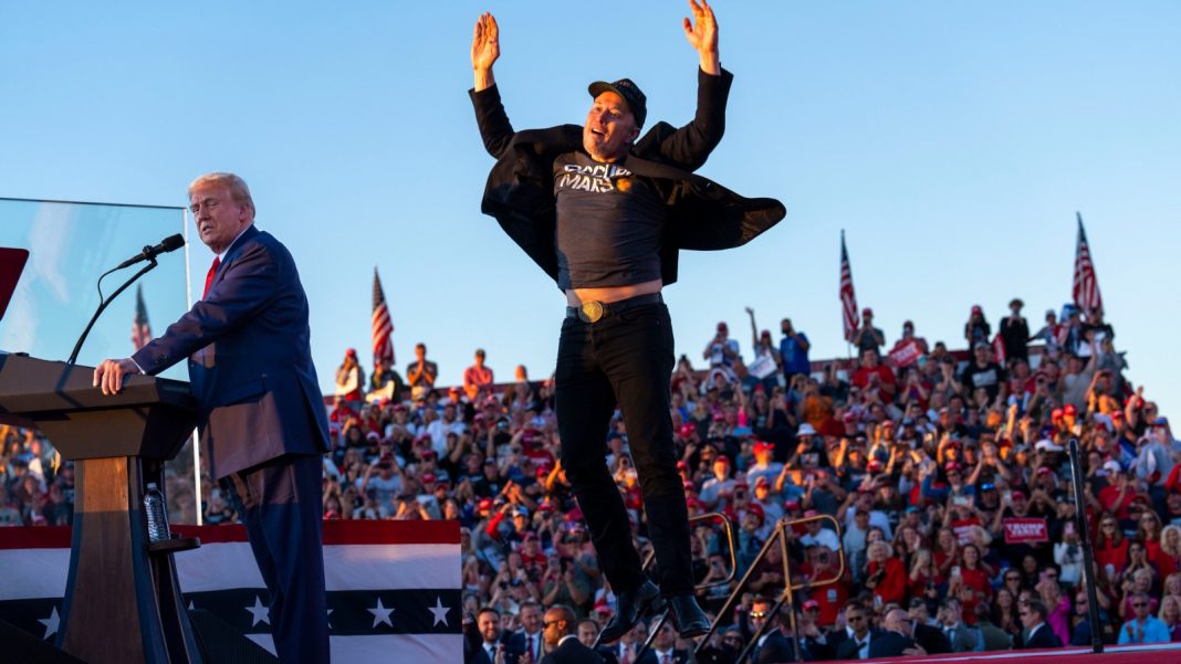 Tesla CEO Elon Musk (R) jumps on stage as he joins former President and Republican presidential candidate Donald Trump during a campaign rally at the site of his first assassination attempt in Butler, Pennsylvania, on October 5, 2024.