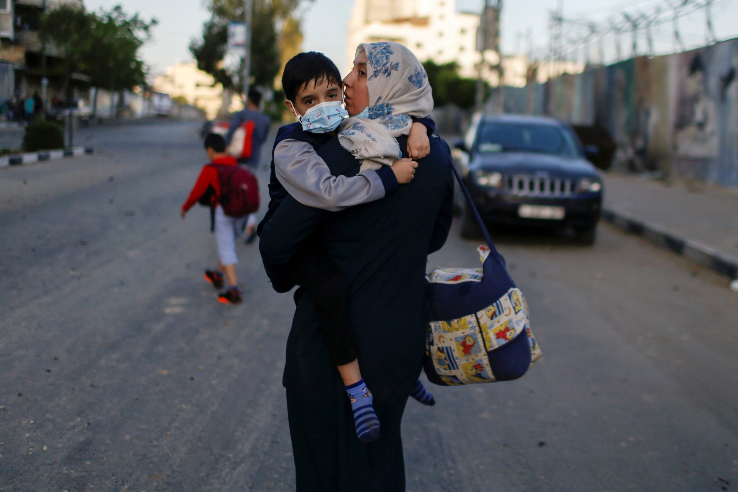 A Palestinian woman carrying her son evacuates after their home was hit by Israeli airstrikes in Gaza City May 12, 2021. | CNS photo/Mohammed Salem, Reuters 