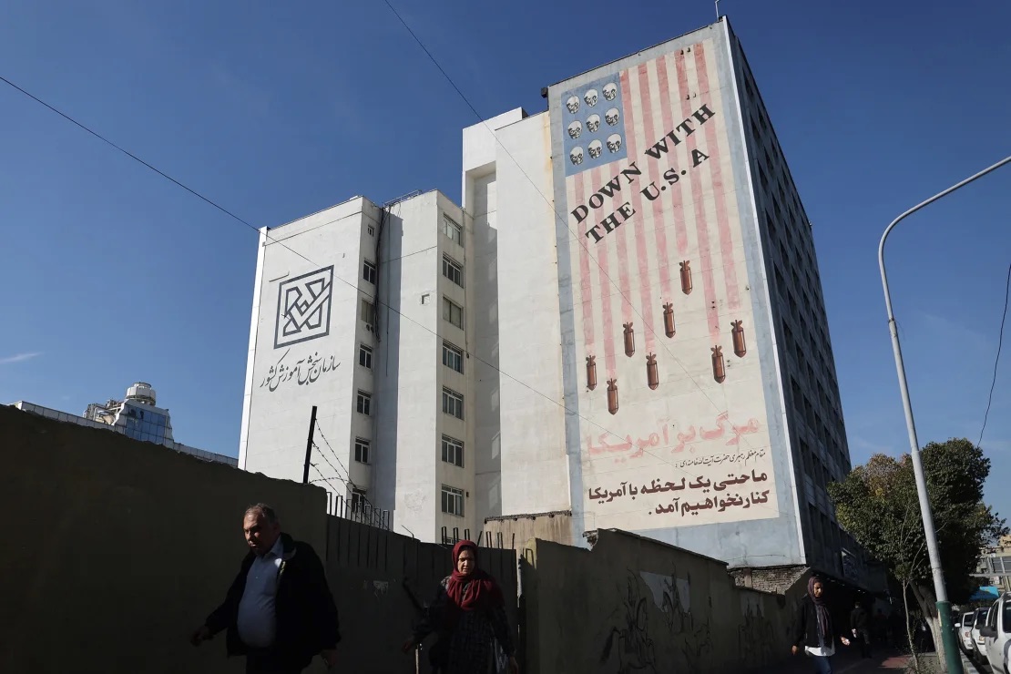 People walk near an anti-U.S. mural on a building after several explosions were heard, in Tehran, Iran, on October 26, 2024. Majid Asgaripour/Wana News Agency/Reuters  