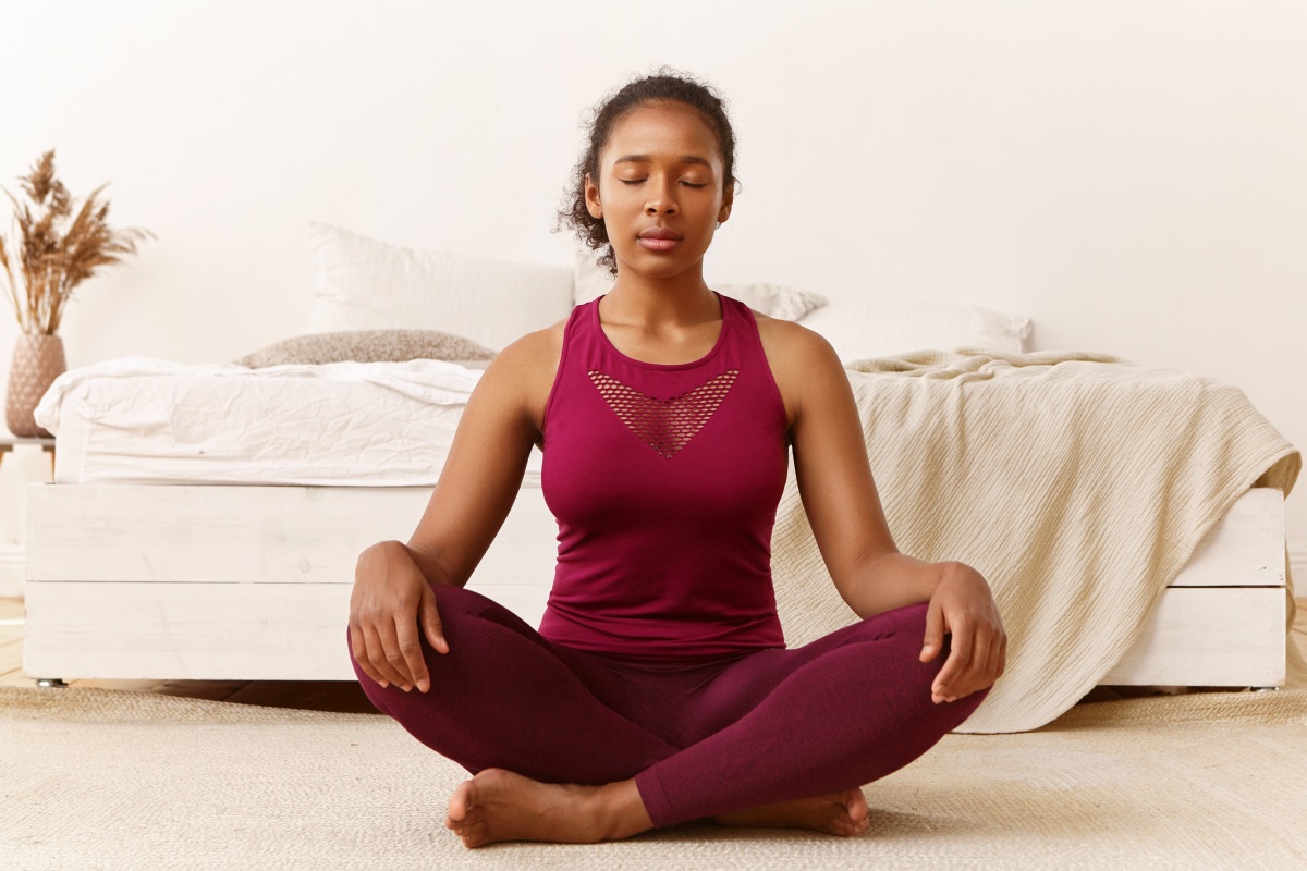 Meditation, peace, balance, zen and harmony concept. Portrait of healthy fit young African woman with eyes closed sitting on floor after yoga practice, meditating, doing breathing exercises, mind,