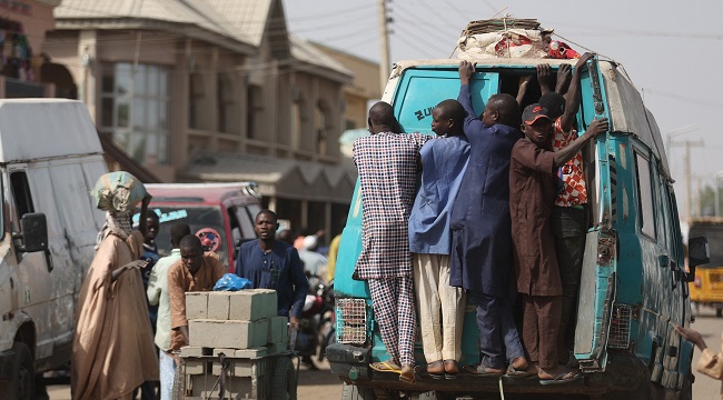 Passengers ride on a minibus near the local food market in Jibia on February 18, 2024. | Kola Sulaimon / AFP