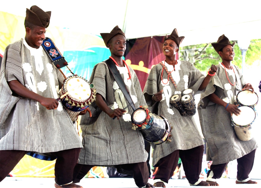 art, yoruba men play the talking drum at an event.