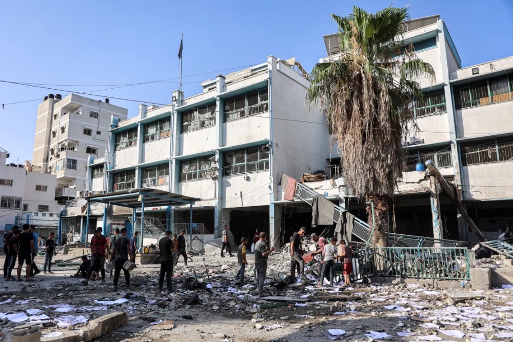 Men and children search through debris in the yard of the Asma school run by UNRWA, in the Shati camp for Palestinian refugees west of Gaza City, in the aftermath of overnight Israeli bombardment on June 25, 2024. | Omar Al-Qattaa/AFP/Getty Images