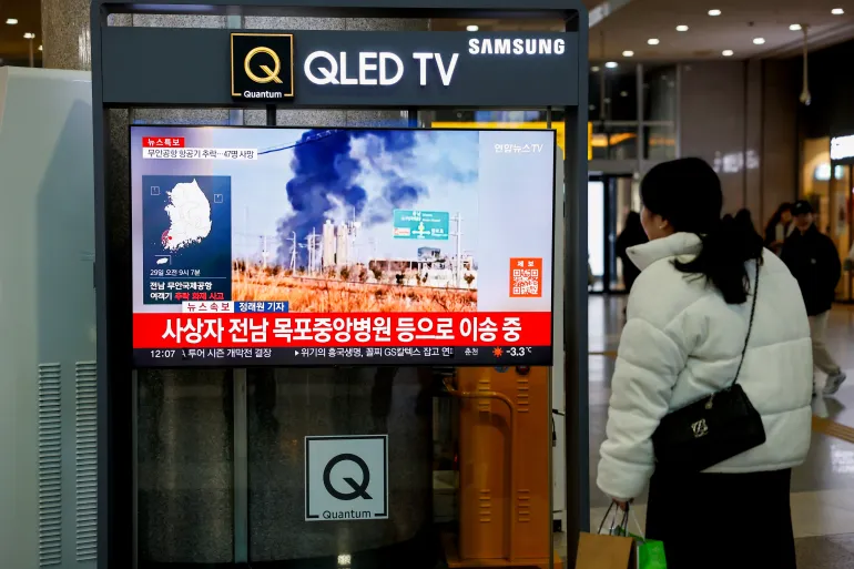 A woman watches a TV screen broadcasting footage of the aircraft crash at Muan International Airport, at a railway station in Seoul, South Korea, December 29, 2024. | Kim Soo-hyeon/Reuters