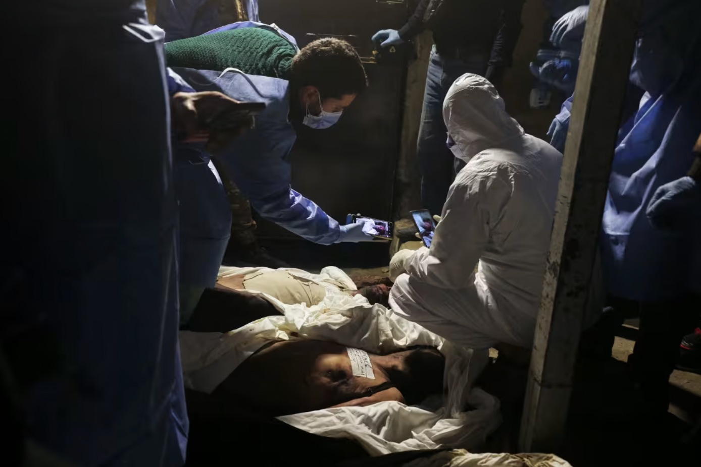  Sanitary workers inspect bodies at a hospital morgue in Damascus on Tuesday, December 10, 2024. | Abdulaziz Ketaz/AFP/Getty Images 