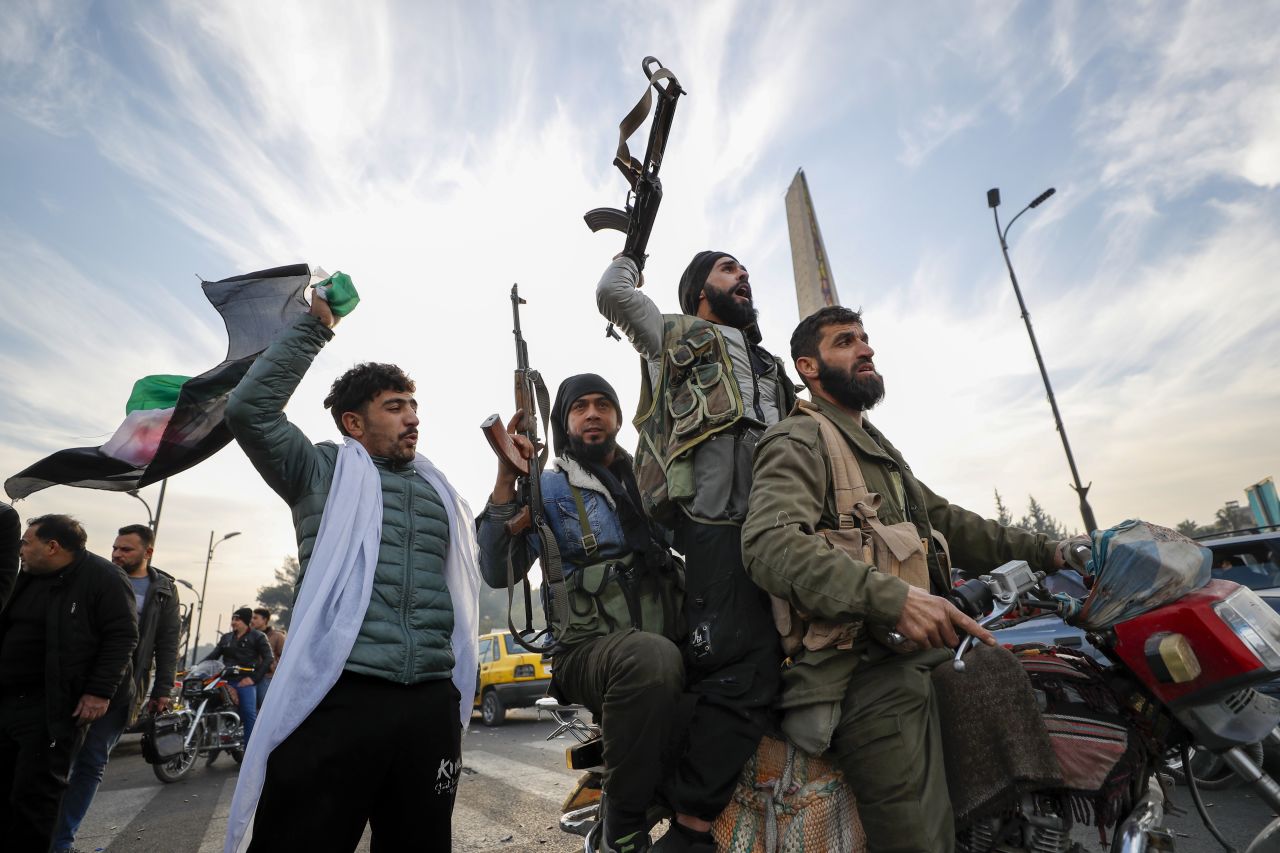 Syrian opposition fighters celebrate after the government collapsed in Damascus on December 8. Omar Sanadiki/AP