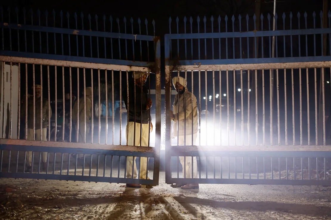 Police stand guard at the gate as vehicles transporting the deported migrants leave the airport in Amritsar, India, on Wednesday. Adnan Abidi/Reuters